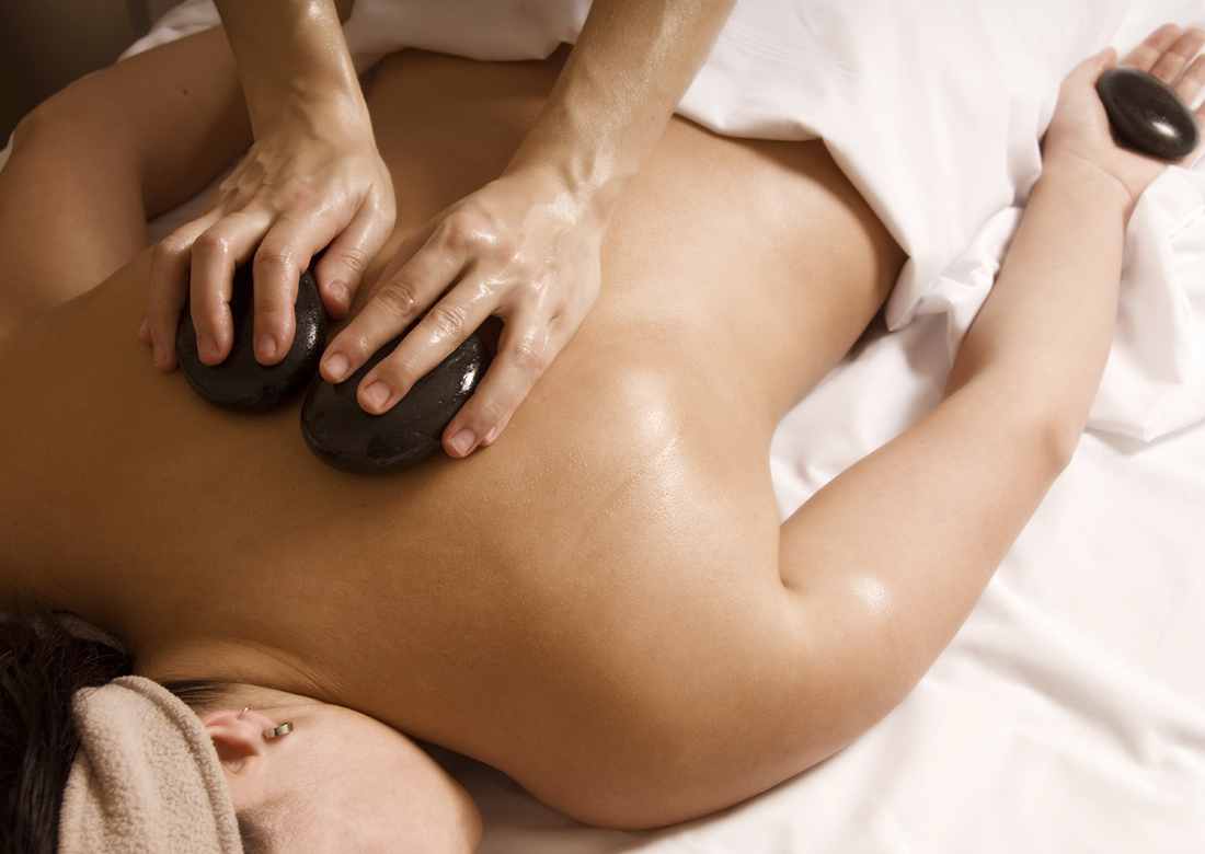 Therapist giving a hot stone massage to client